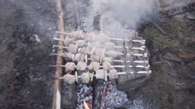 Yakışıklı adam ormanda ateşte et şişi pişiriyor.