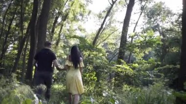 Yakışıklı bir adam ve güzel bir kız göl kenarındaki ormanda el ele yürüyorlar.