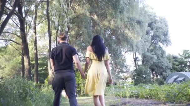 ハンサムな男と可愛い女の子は湖の近くの森を歩いている手を握って — ストック動画