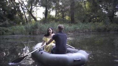 Yakışıklı bir adam ve güzel bir kız gölde kauçuk bir teknede yüzerler.