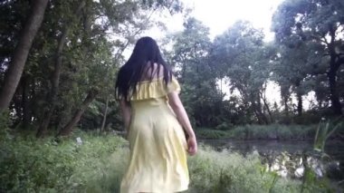 Güzel kız gün batımında gölün yanındaki ormanda yürür.