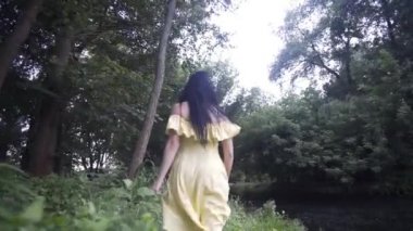 Güzel kız gün batımında gölün yanındaki ormanda yürür.