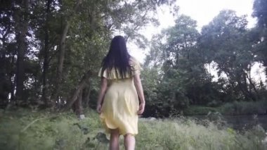 Güzel kız gün batımında gölün yanındaki ormanda yürür.