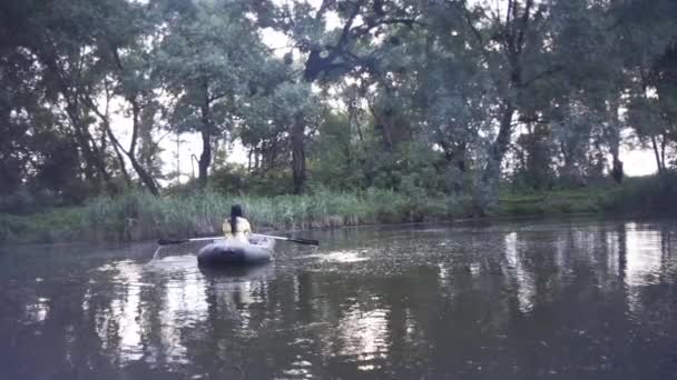 美丽的姑娘晚上在湖上的一艘橡皮艇上游泳 — 图库视频影像