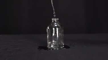 Su yavaş çekimde güzel bir şekilde akar güzel bir cam şişeye.