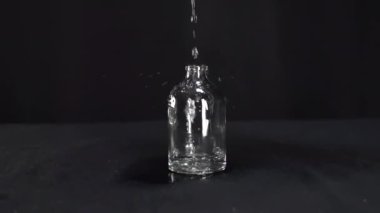 Su yavaş çekimde güzel bir şekilde akar güzel bir cam şişeye.