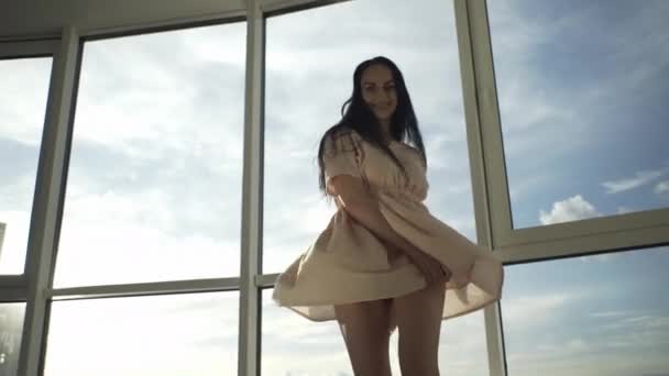 美丽的女孩站在一座高楼大厦的窗前 目光炯炯地看着摄像机 — 图库视频影像
