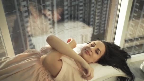 美しい景色を望む高い家の窓の近くのカメラにポーズをとる美しい少女 — ストック動画