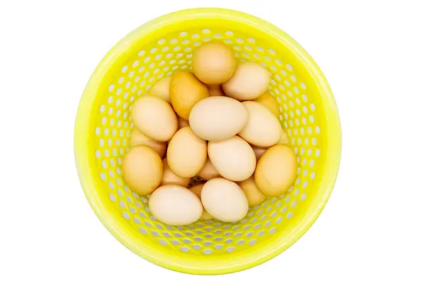 Beyaz arka planda sarı sebze sepetli çiftlik yumurtaları.