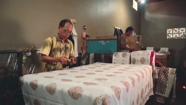 Мужчины штампуют батик на маленькой фабрике в Индонезии — стоковое видео