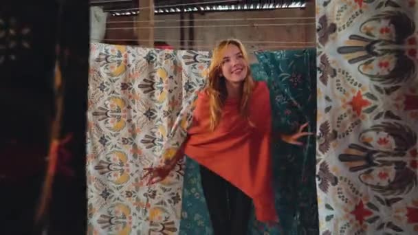 Белая женщина, проходящая сквозь ряды батиковой ткани — стоковое видео