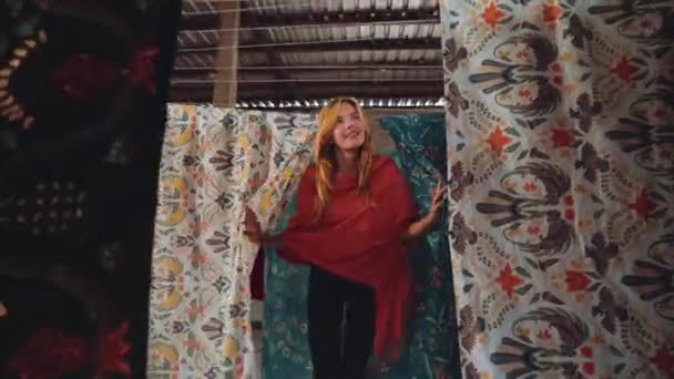 Caucasian woman walking through rows of batik fabric — Stock Video