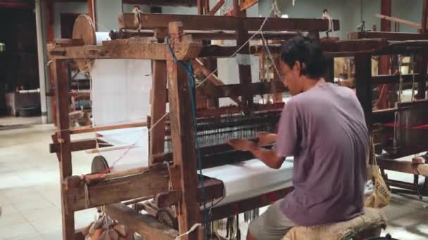 Indonesischer Mann webt Stoff mit Fuß-Tretwebmaschine — Stockvideo
