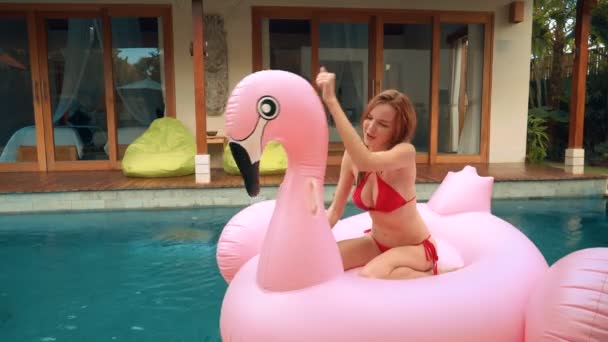 Giovane donna sul grande Flamingo gonfiabile piscina galleggiante — Video Stock