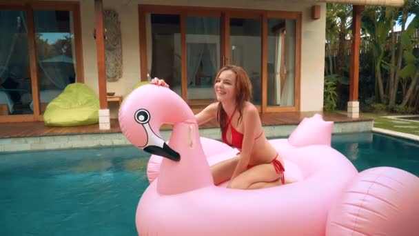 Ung kvinna på big Flamingo uppblåsbara Pool Float — Stockvideo