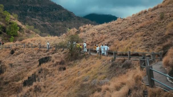 Gente balinesa en ropa de ceremonia caminando desde el templo de la colina Pura Batu Korsi — Vídeo de stock