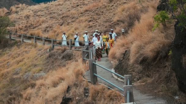 Balinese mensen in ceremonie kleding lopen van Pura Batu Korsi heuvel tempel — Stockvideo