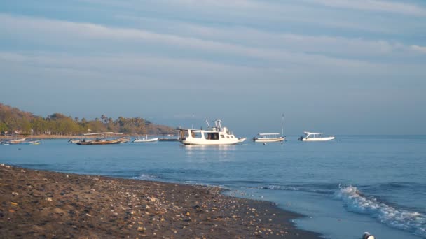 Playa de arena negra y pequeños barcos blancos en el mar — Vídeos de Stock