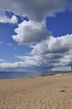 Sandy beach and white clouds in a blue sky.