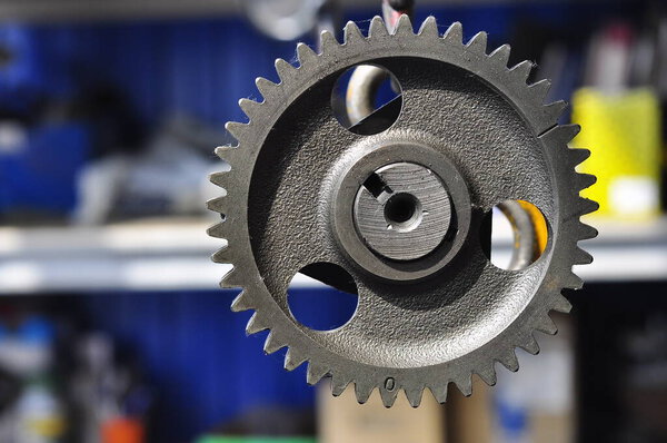 Metal gear wheel. The camshaft of the engine blurred background. Part of the car's engine.