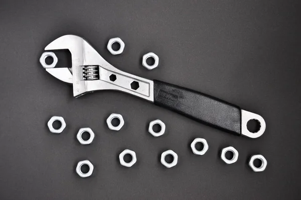 Adjustable wrench with  nuts on black background