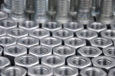 Arka planda metal cıvatalar ve fındıklar. Çelik cıvatalar ve fındık desenleri. Fındık ve cıvata takımı.