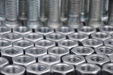Arka planda metal cıvatalar ve fındıklar. Çelik cıvatalar ve fındık desenleri. Fındık ve cıvata takımı.
