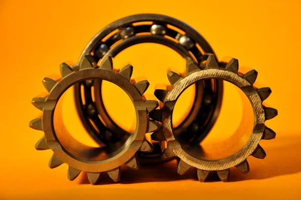 Sarı arka planda metal dişliler ve bilye. Arabanın bir parçası.