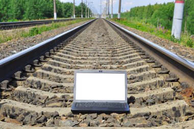 Tren raylarında siyah dizüstü bilgisayar. Demiryolu mesafeye gidiyor. Seyahat endüstrisi