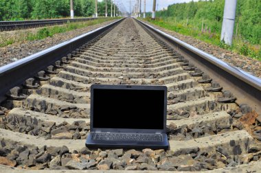 Tren raylarında siyah dizüstü bilgisayar. Demiryolu uzaklaşıyor..