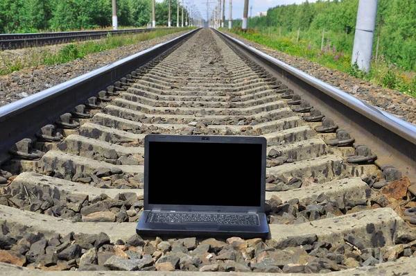 Tren raylarında siyah dizüstü bilgisayar. Demiryolu uzaklaşıyor..