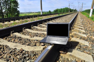 Black laptop on railway. Railway going into the distance.