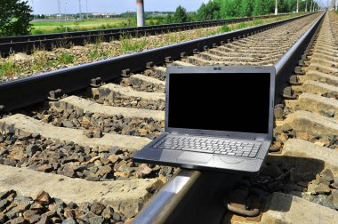 Tren raylarında siyah dizüstü bilgisayar. Seyahat endüstrisi