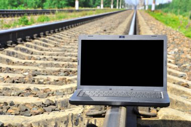 Tren raylarında siyah dizüstü bilgisayar. seyahat işi