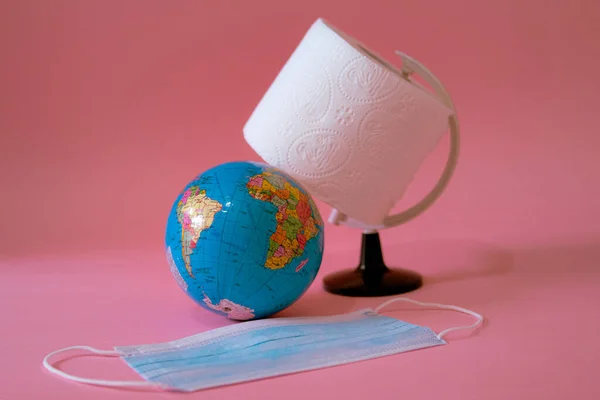 Jord glob, toalettpapper och ansiktsmask på rosa bakgrund — Stockfoto