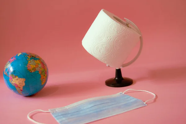 Globe terrestre, papier toilette et masque facial sur fond rose — Photo