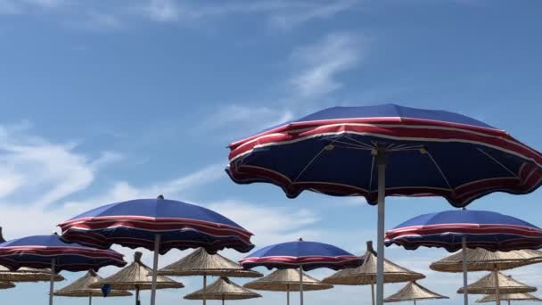 Wiatr wieje. Plaża niebieskie parasole nad Morzem Adriatyckim w Albanii, Durres — Wideo stockowe