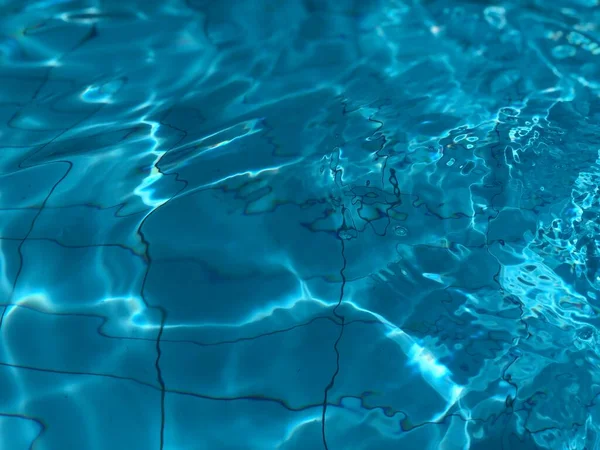 Μπλε νερό της πισίνας με αντανάκλαση ήλιου.Αφηρημένο φόντο του νερού. — Φωτογραφία Αρχείου