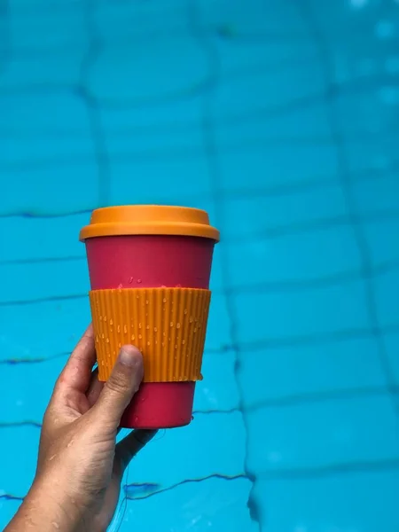 Γυναίκα απολαμβάνει τον καφέ σε μια επαναχρησιμοποιήσιμη κούπα μπαμπού στην πισίνα — Φωτογραφία Αρχείου