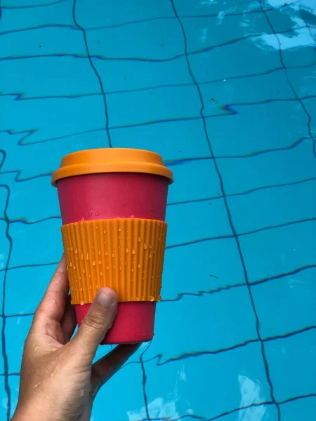 Γυναίκα απολαμβάνει τον καφέ σε μια επαναχρησιμοποιήσιμη κούπα μπαμπού στην πισίνα — Φωτογραφία Αρχείου