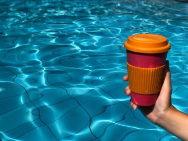 Yüzme havuzunda kahve içen bir kadın.