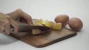 Kadın elinin yakın görüntüsü, akşam yemeği için odun kesme tahtasının kahverengi renginde patates doğrama..