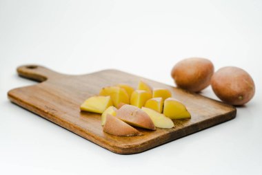 Beyaz arka planda izole edilmiş, seçici odaklı bir kesim tahtasındaki patates.