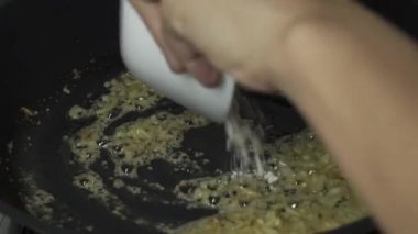 Mutfağı sarımsaklı kızartma tavasıyla ahşap bir kaşık ve kızartma tavasıyla kızartmak, yağda kızartmak ve sonra şefin elleri tavaya un koymak