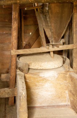 Değirmen taşı ve tahıl zıpzıpzıpıyla bir su değirmeni manzarası.