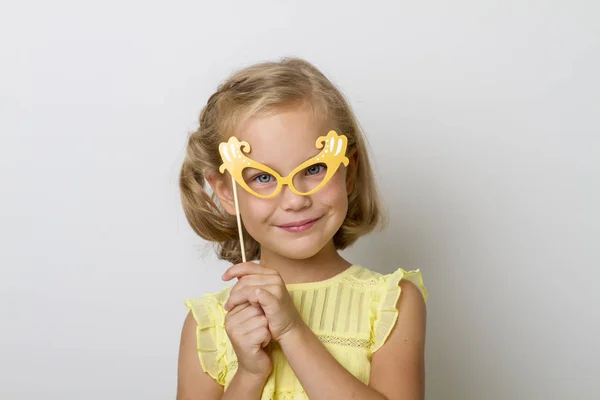 Chica divertida con accesorios de papel. niño sosteniendo gafas en palo . —  Fotos de Stock