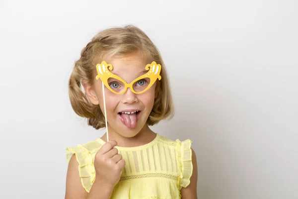 Chica divertida con accesorios de papel. niño sosteniendo gafas en palo . —  Fotos de Stock