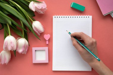 Not defterinde pembe tablo üzerinde yazma kadın eli.