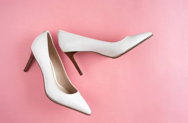 Light white high heels isolated on a bright pink pastel background. Fashion concept