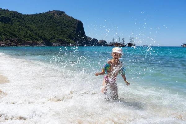 Gelukkig kind dat in de zee speelt. Kind heeft plezier op het strand. — Stockfoto